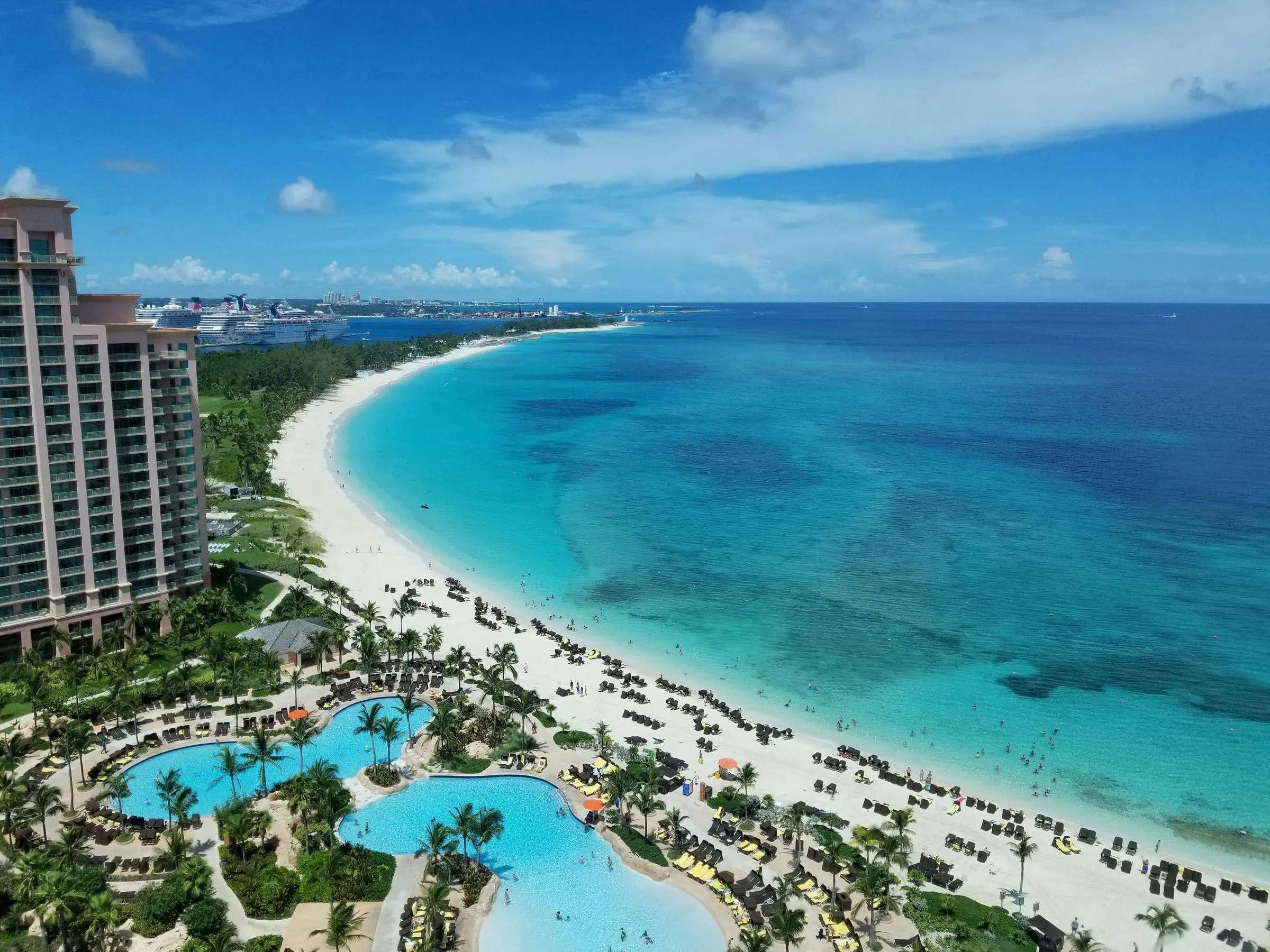 Pools, palms, and open water at a Bahamas beach resort