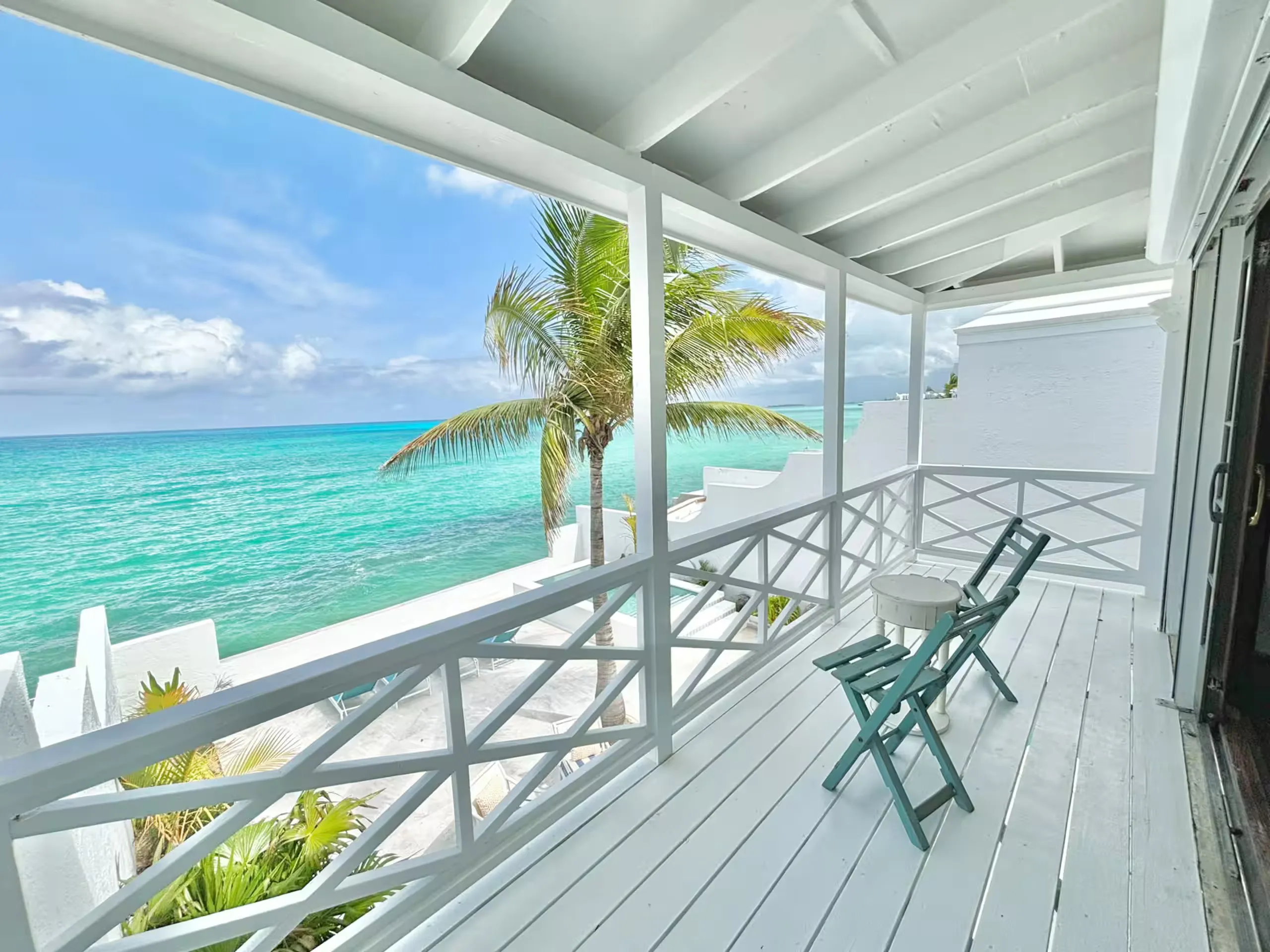 Upper balcony with teal chairs overlooking the ocean