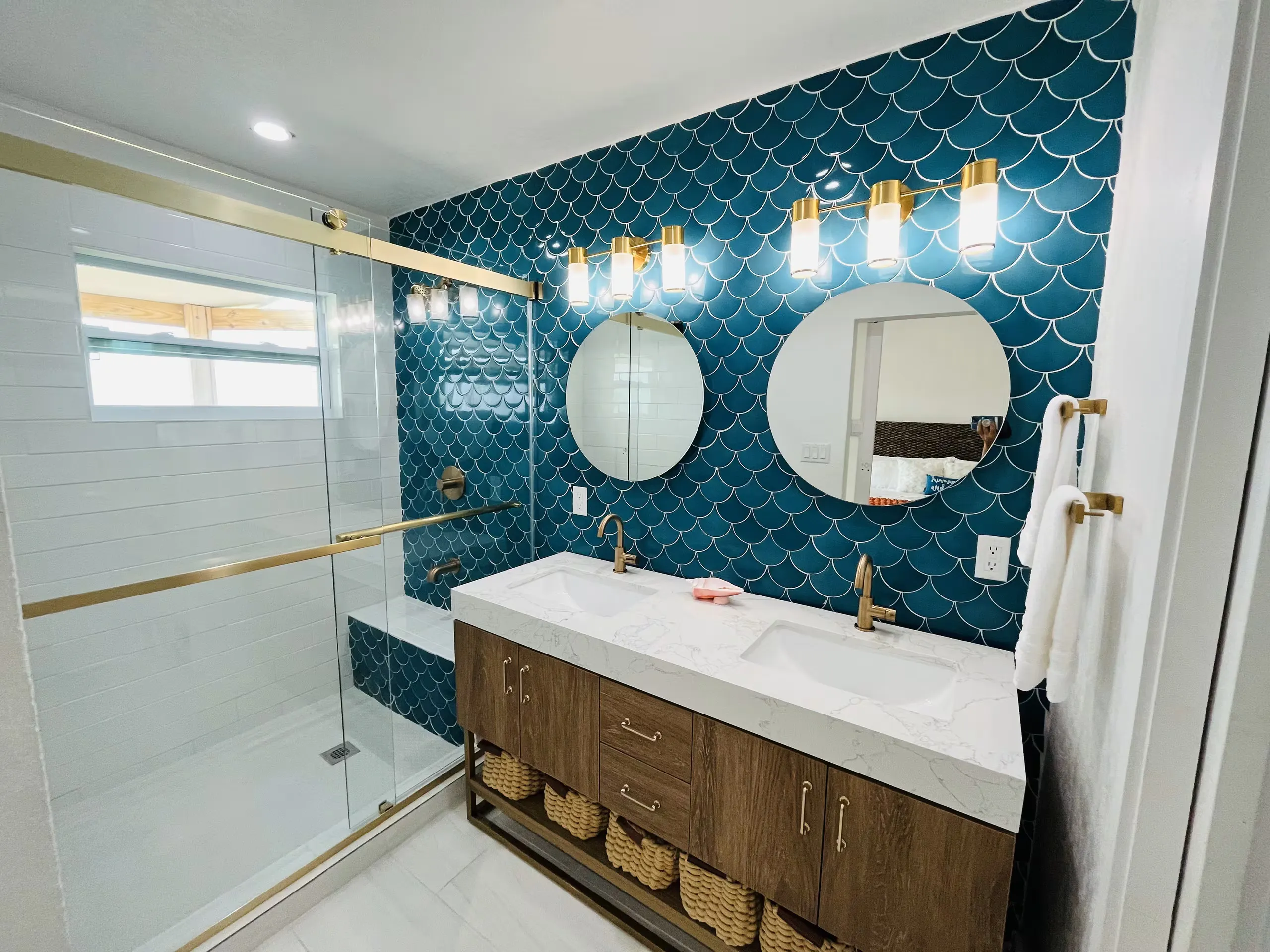 Bathroom with teal fish-scale tile and a double vanity
