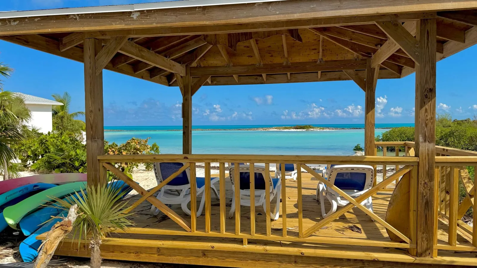 Wooden beach gazebo with lounge chairs looking out to turquoise sandbar water