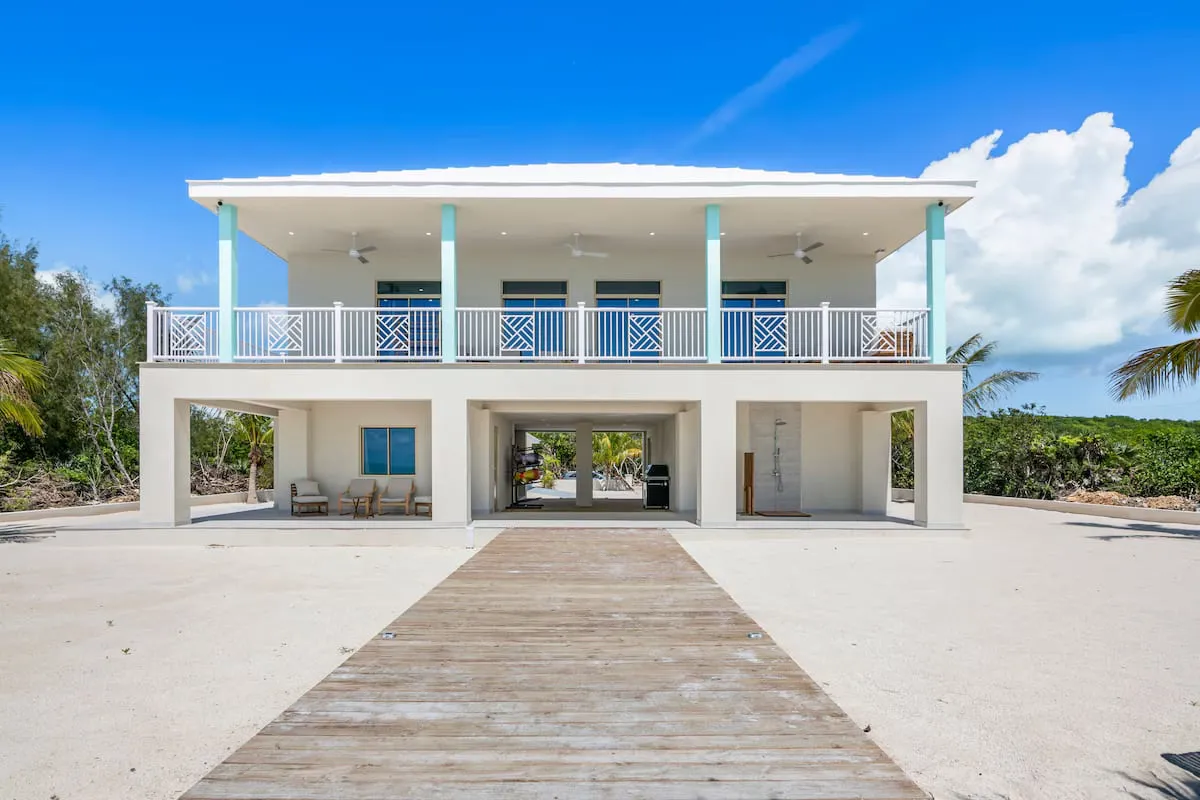 Beachfront facade with upper balcony and wooden boardwalk from the sand