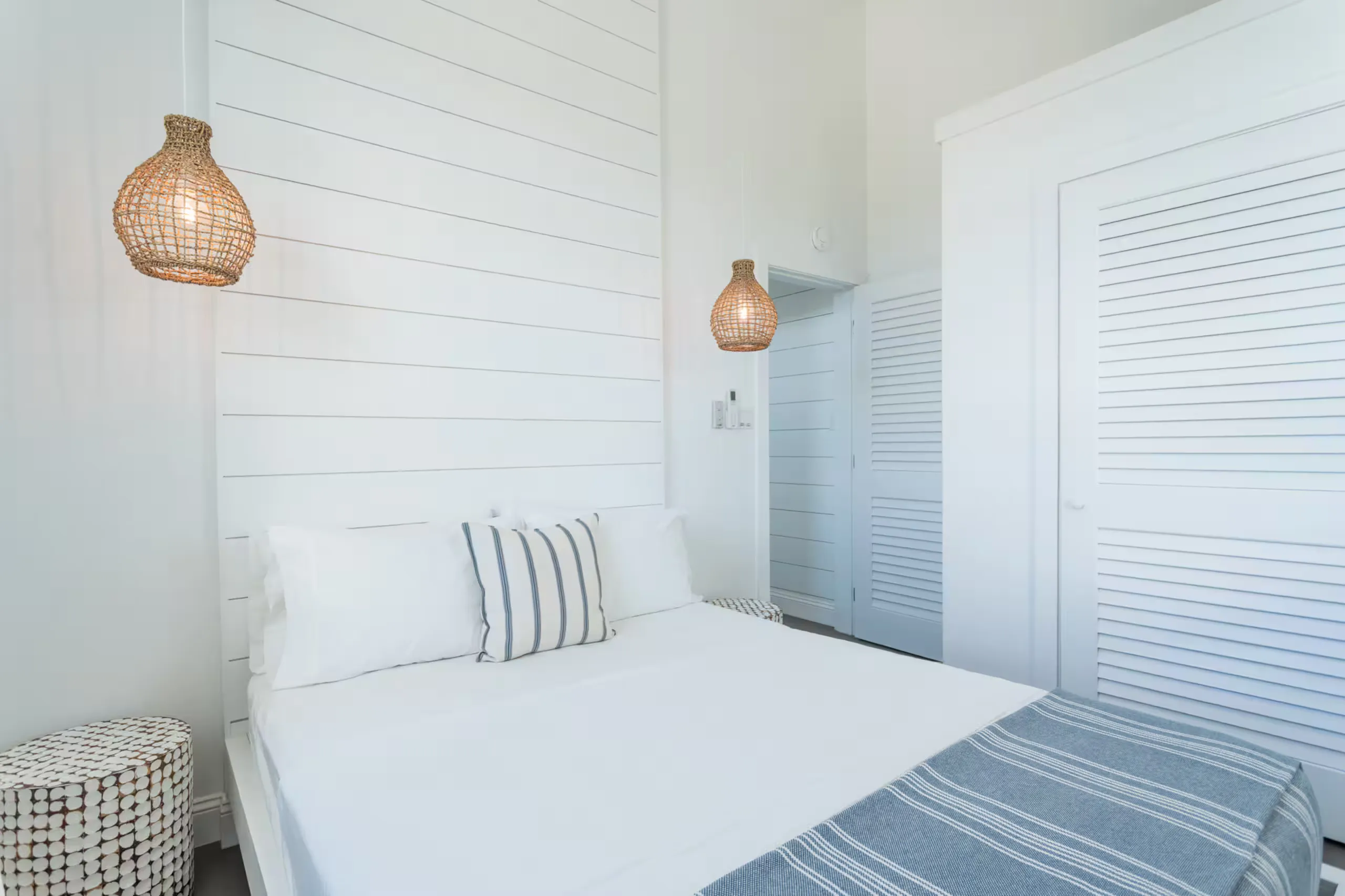 Bedroom with woven pendant lights and a striped throw pillow