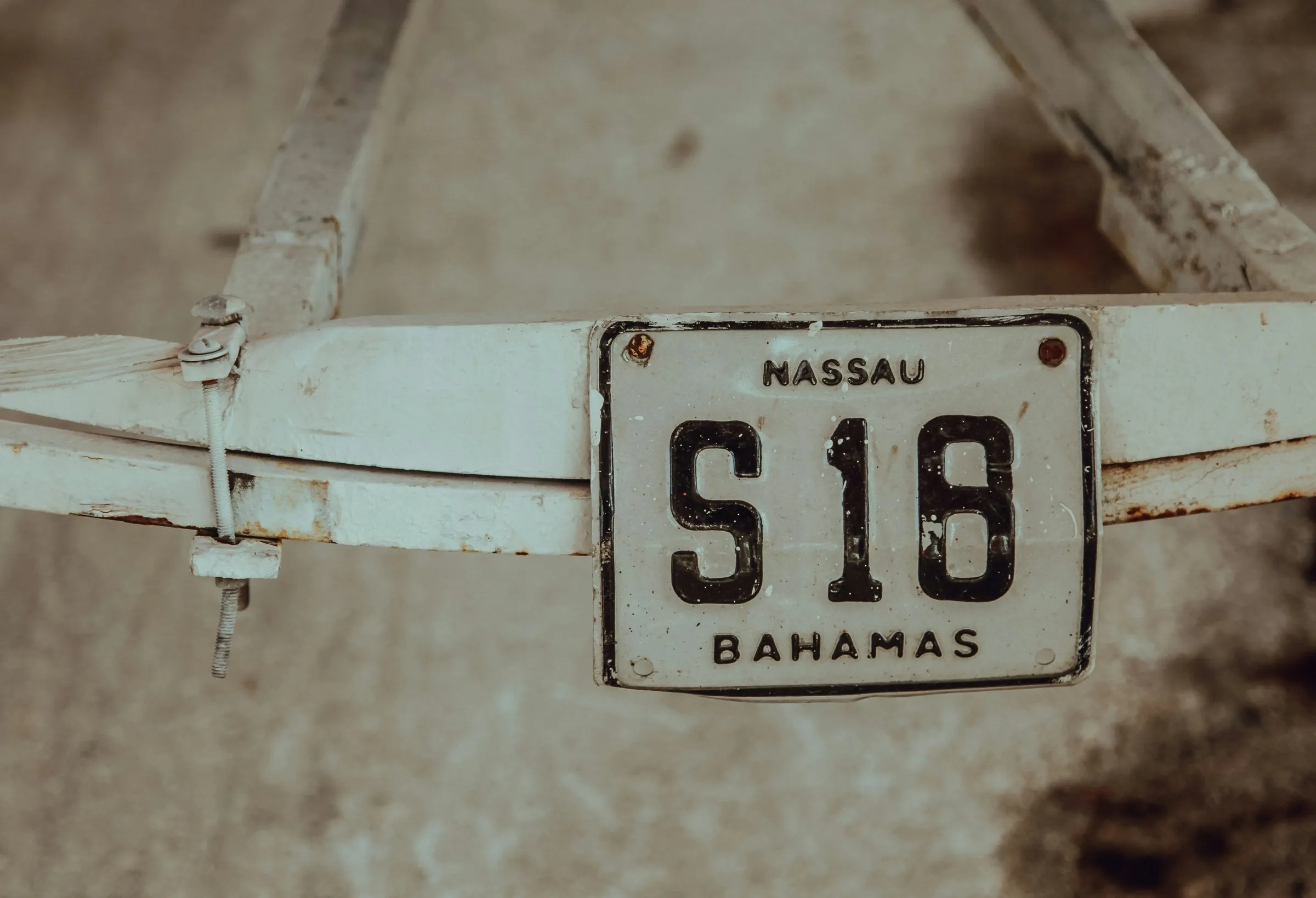 A weathered Nassau license plate on an old cart