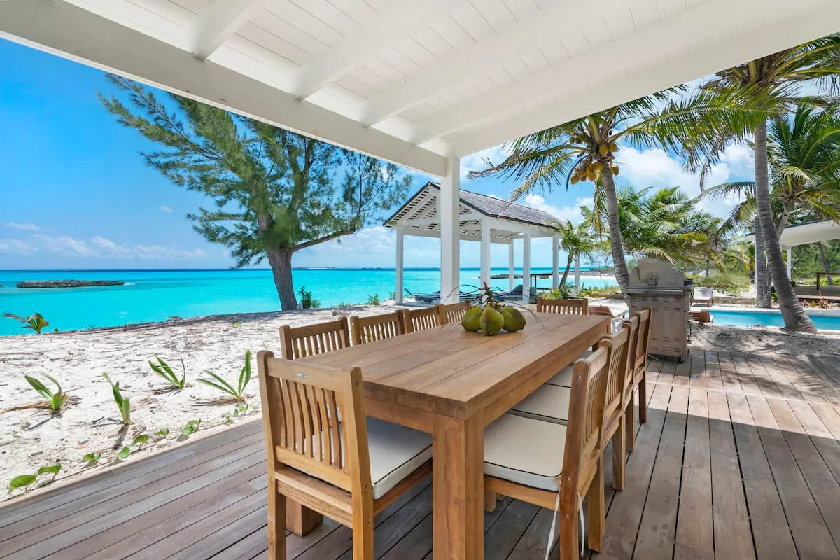Covered wooden dining deck on the sand with ocean beyond