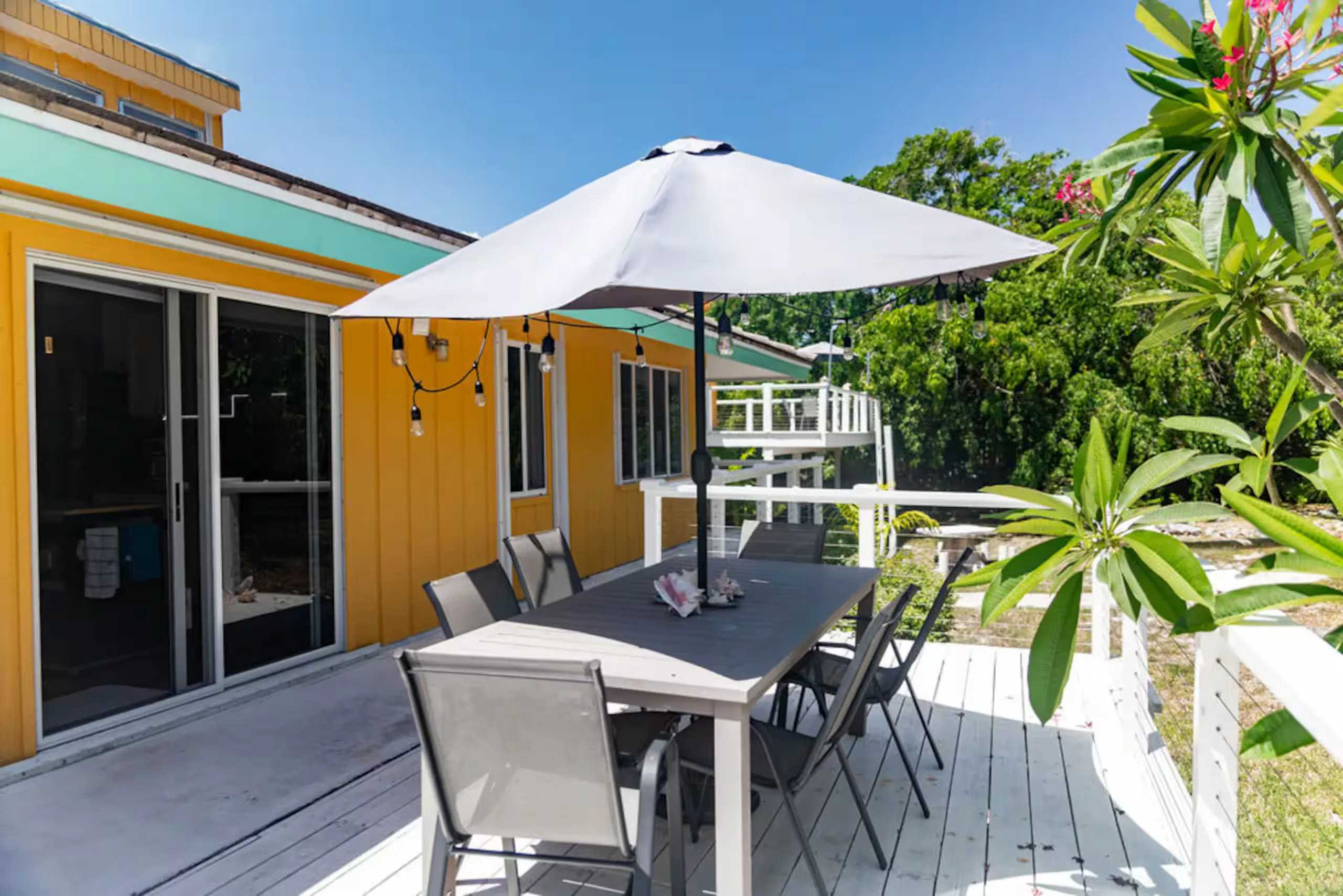 Deck dining table with an umbrella, beside the frangipani plant