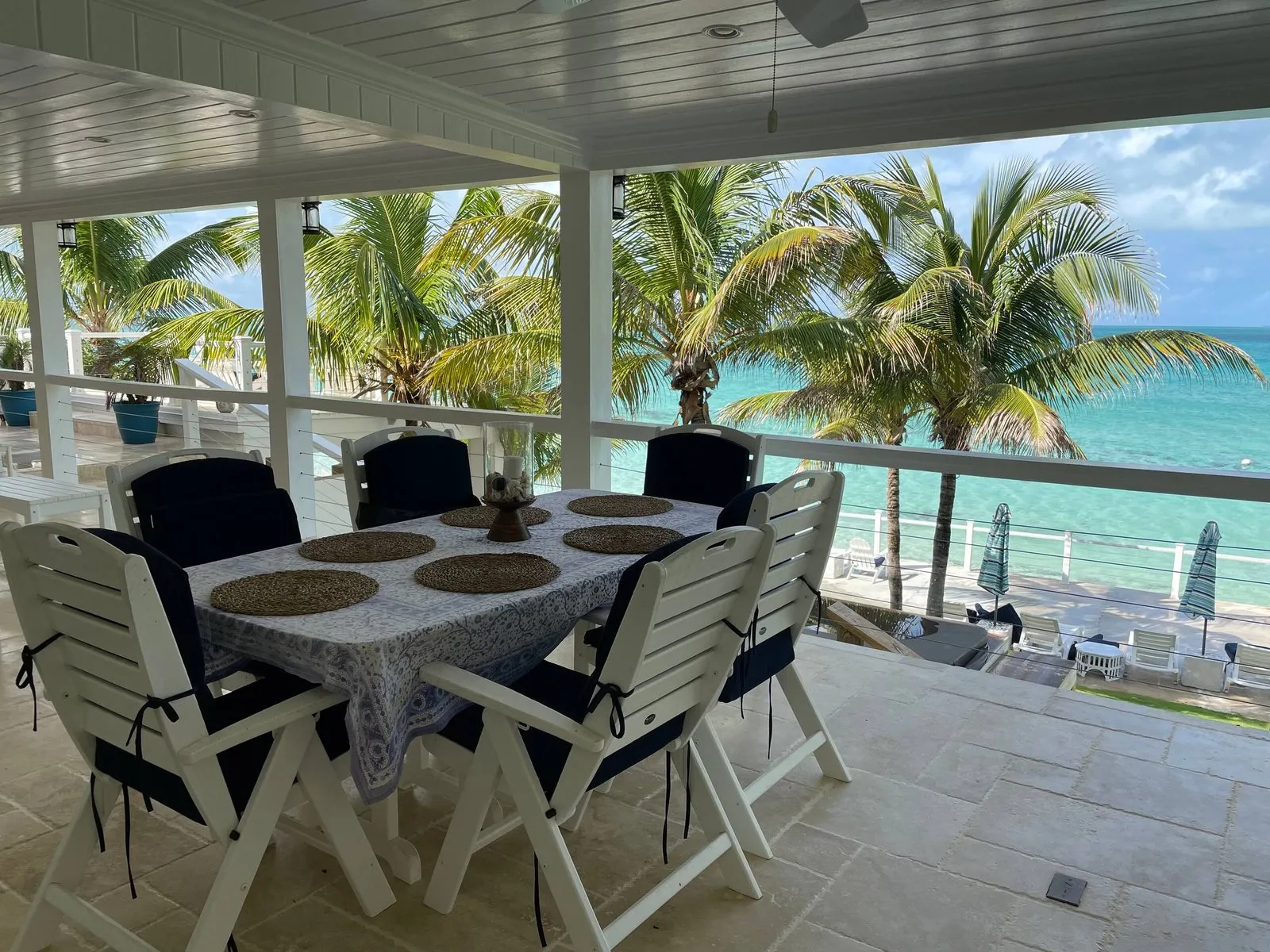 Covered dining deck with a table set for six and an ocean view