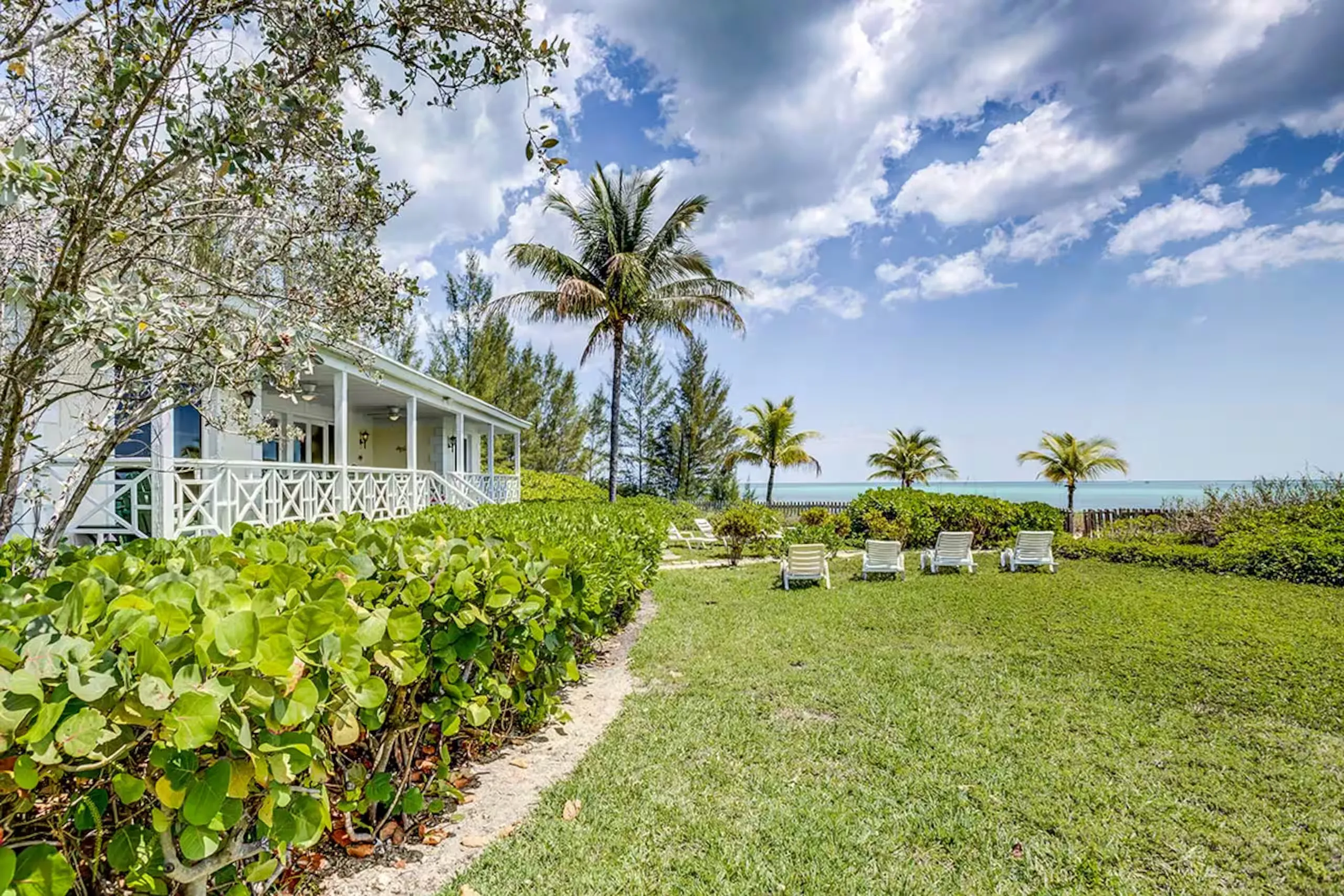 House exterior with lawn and loungers facing the water