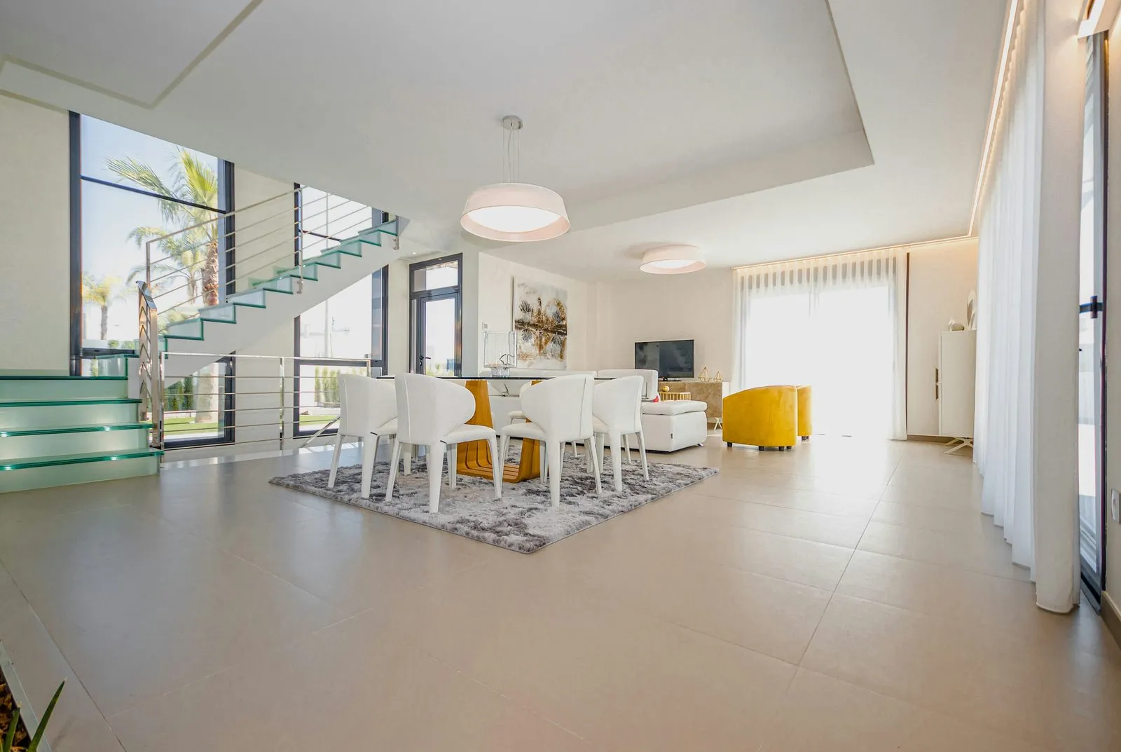 A bright, wide-angle shot of a modern villa living and dining area
