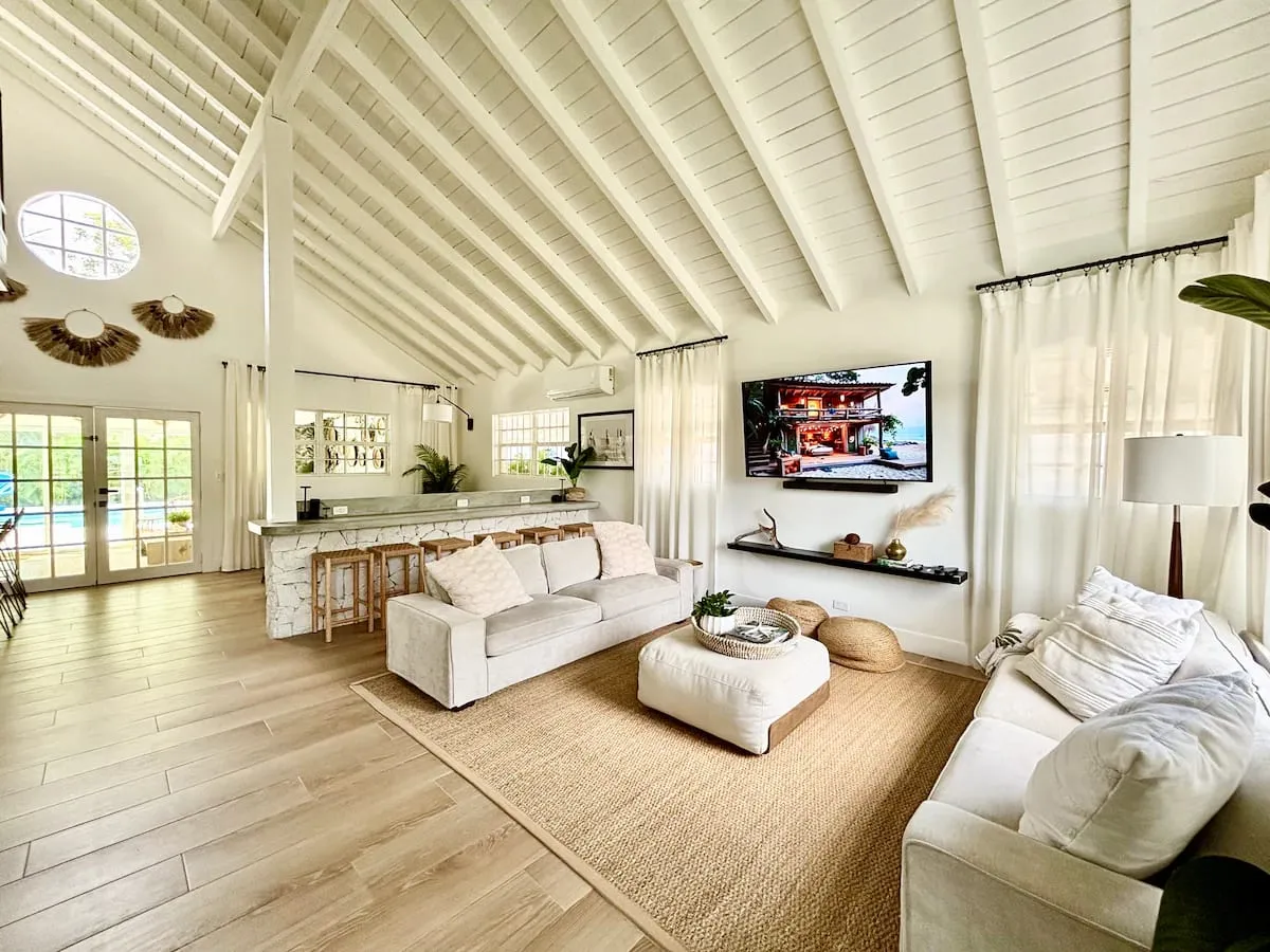 Open great room with vaulted beamed ceiling, sofas, and a breakfast bar