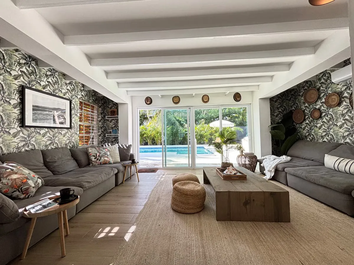 Living room with tropical wallpaper opening through glass doors to the pool