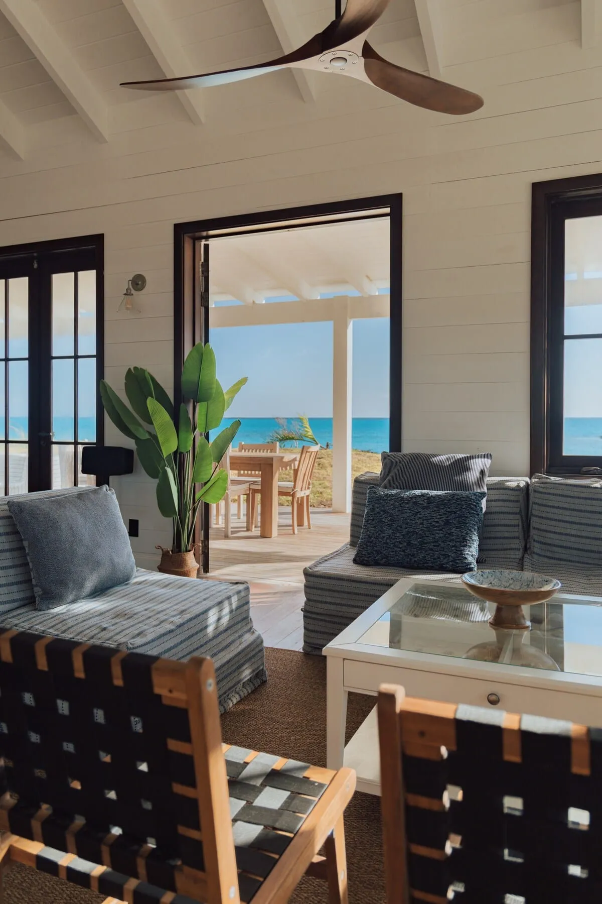 Living room opening onto the deck with turquoise water beyond