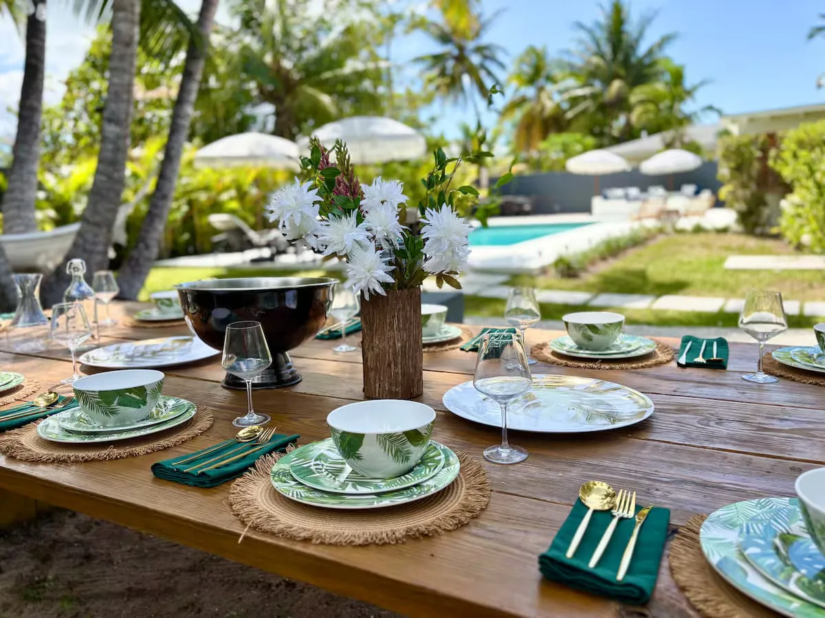 Long outdoor dining table set for a group meal beside the pool