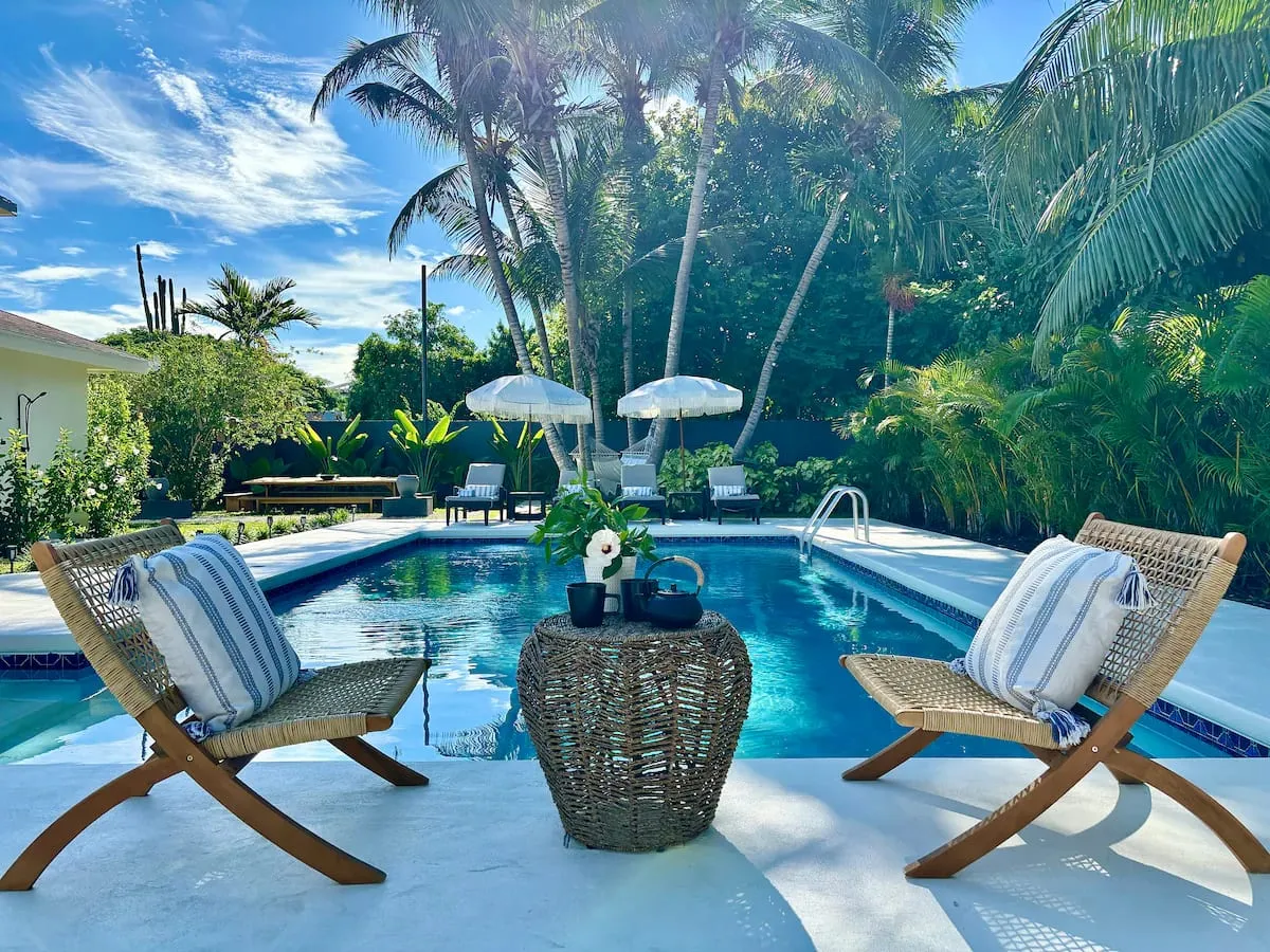 Private pool with loungers under white umbrellas and tropical landscaping