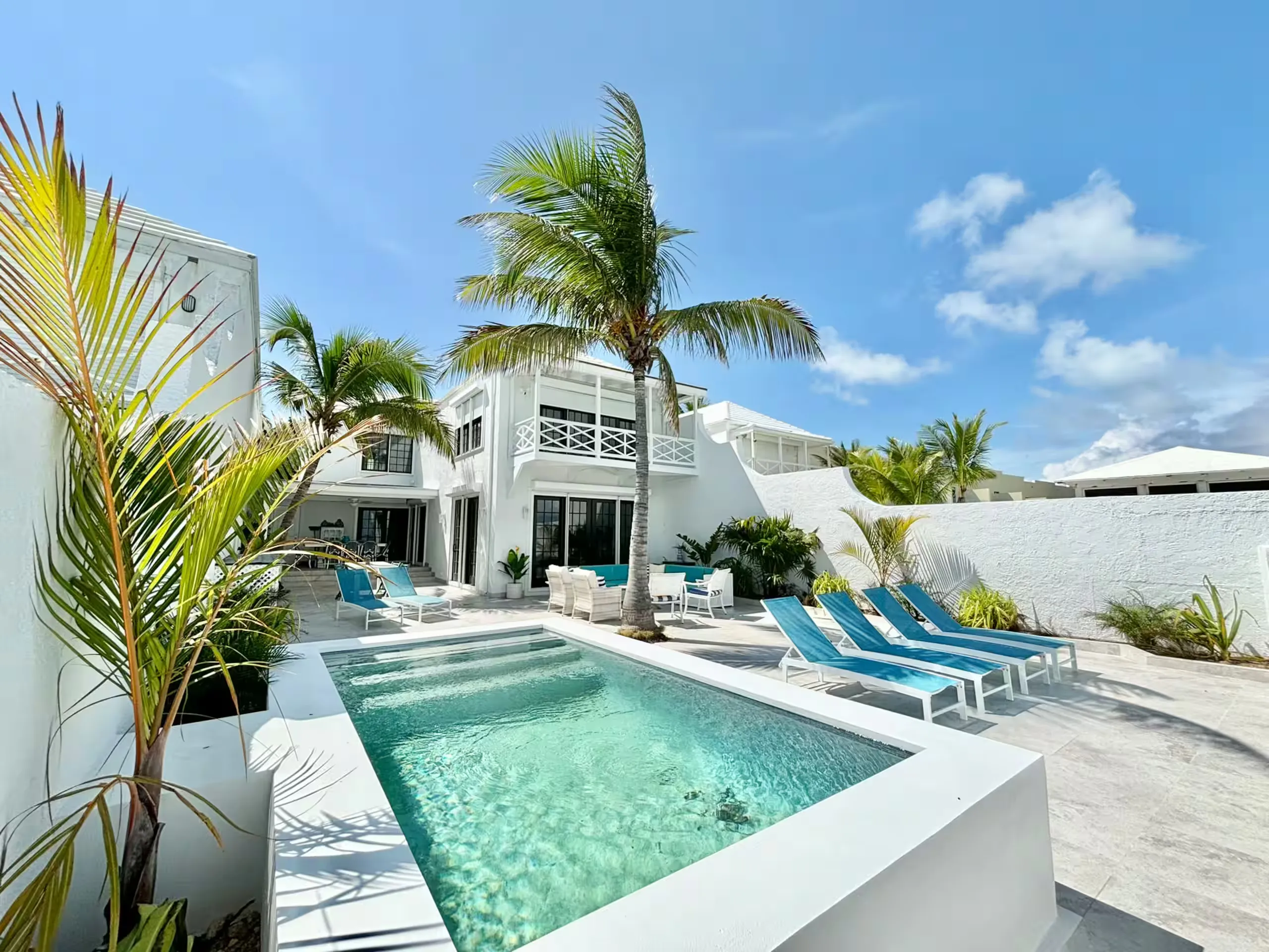 Private pool and patio with blue loungers in front of the white villa