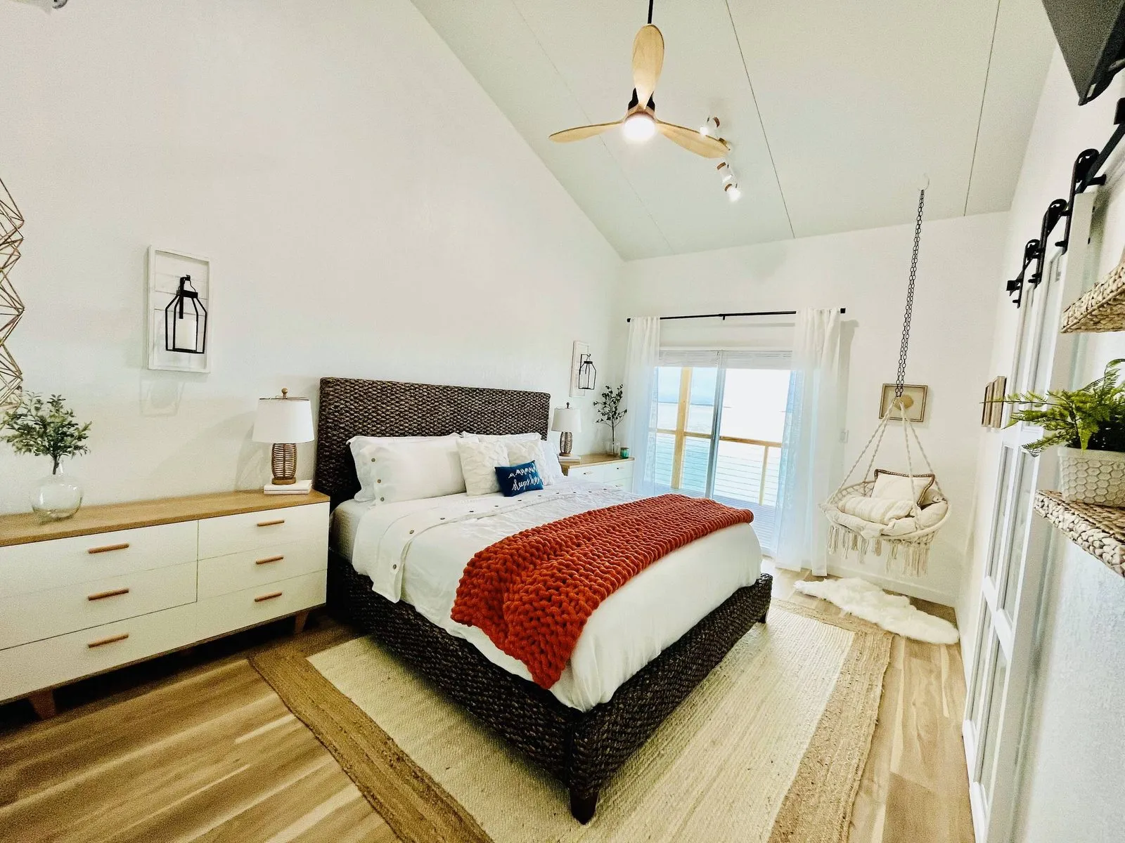 Primary bedroom with a woven headboard and hanging chair