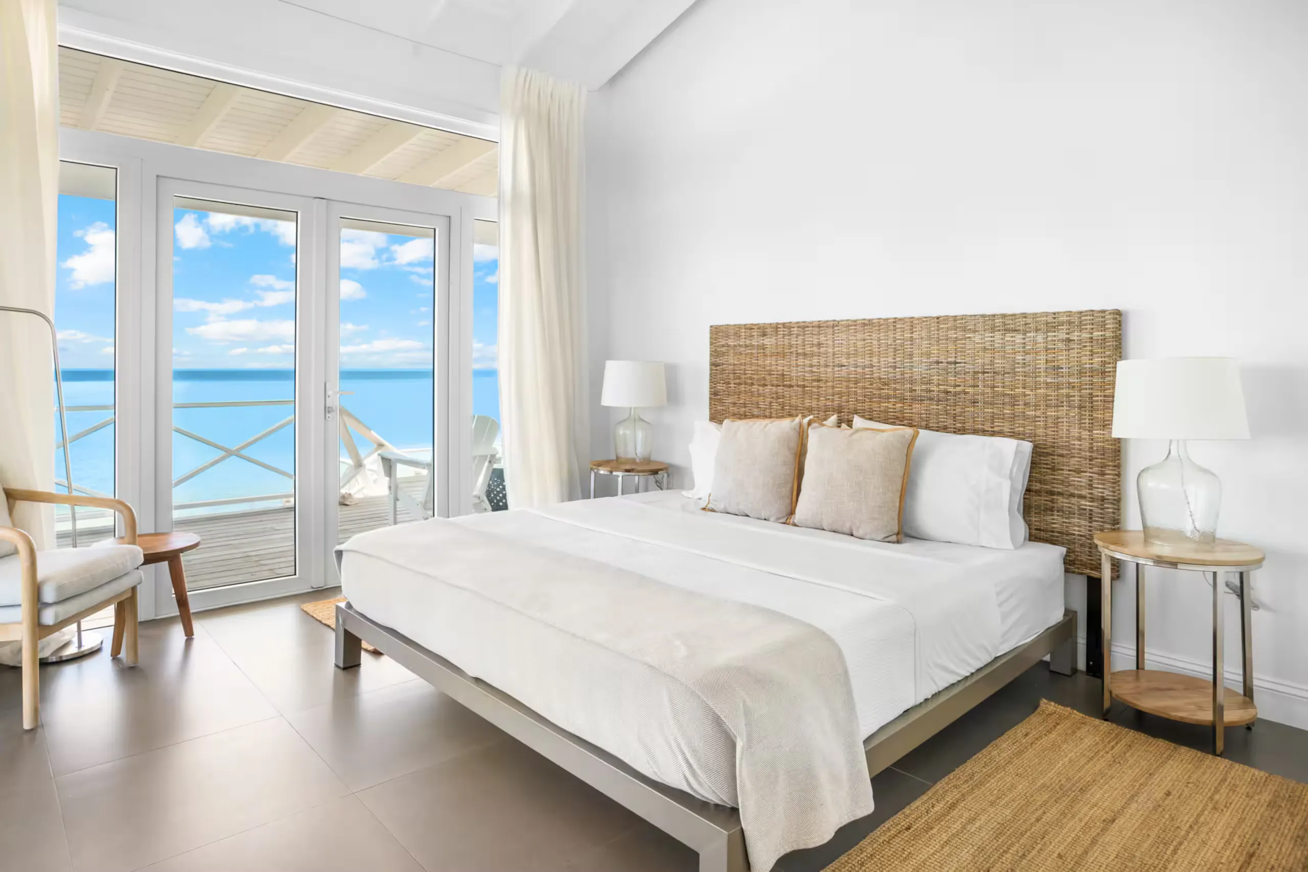 Primary bedroom with a woven headboard and ocean-view balcony doors
