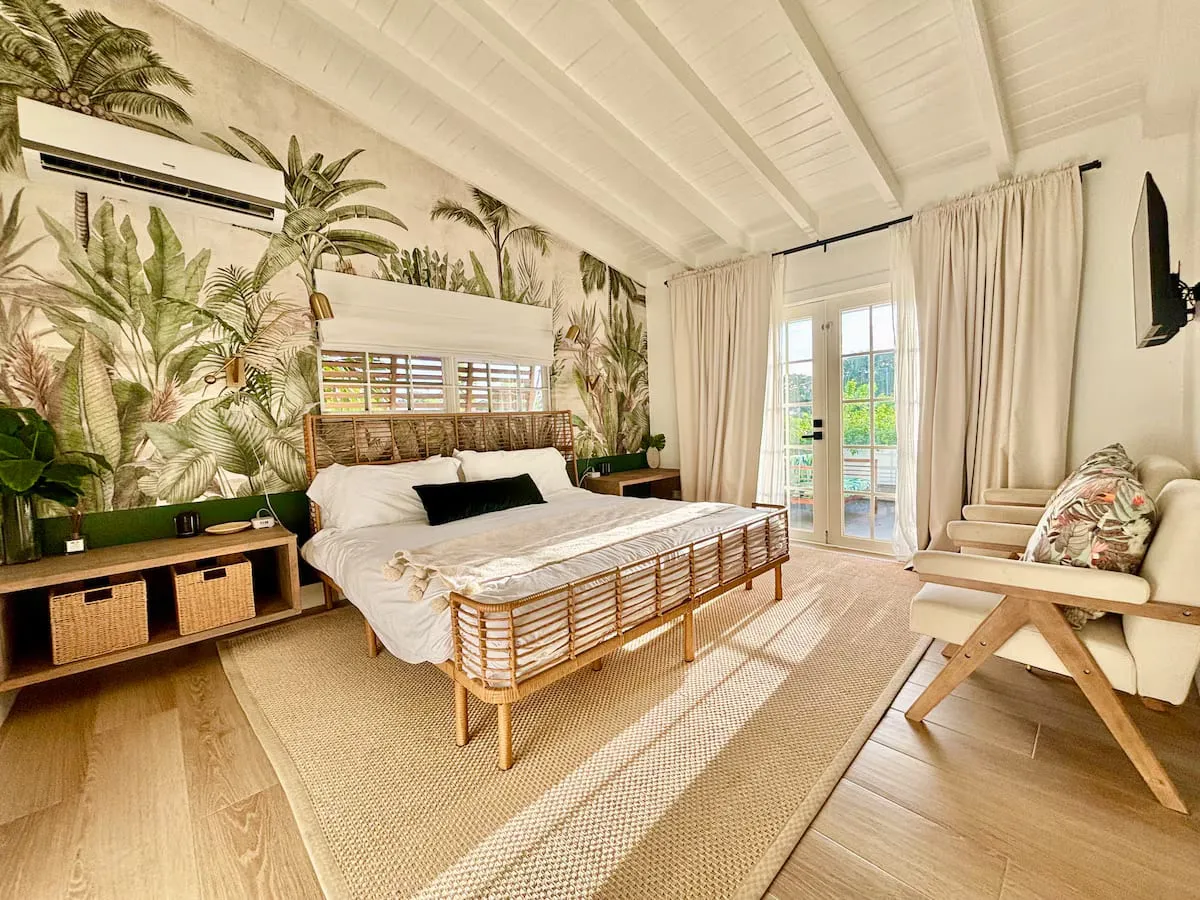 Bedroom with a botanical mural, rattan bed, and French doors
