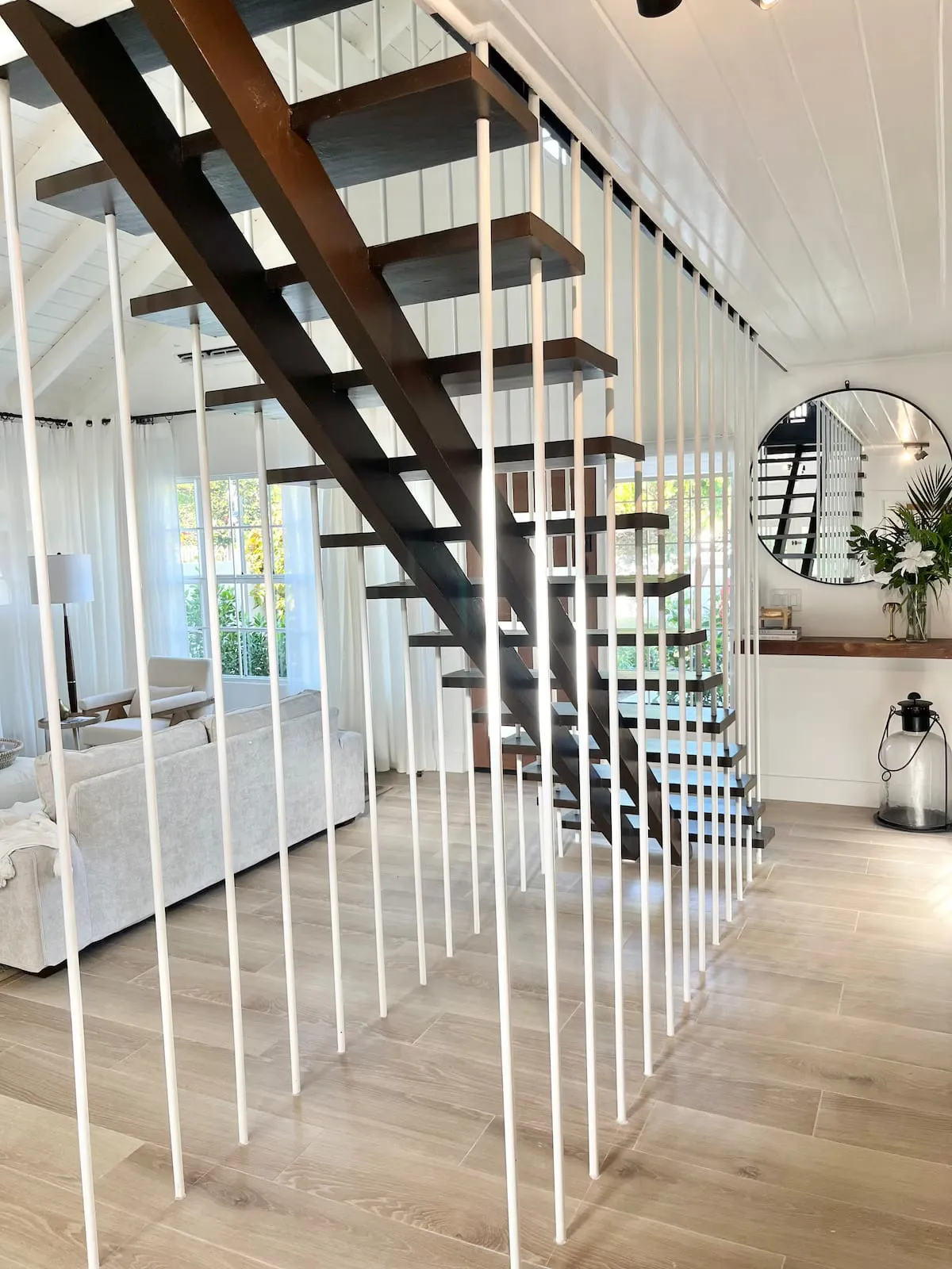 Modern wood staircase with white vertical rods beside the living area