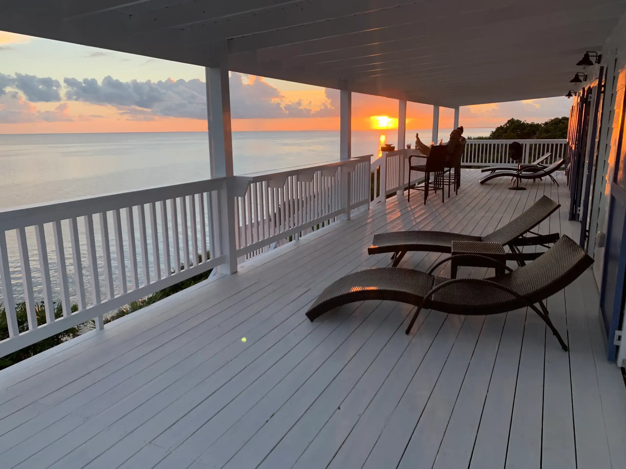 Covered deck with lounge chairs facing the sunset