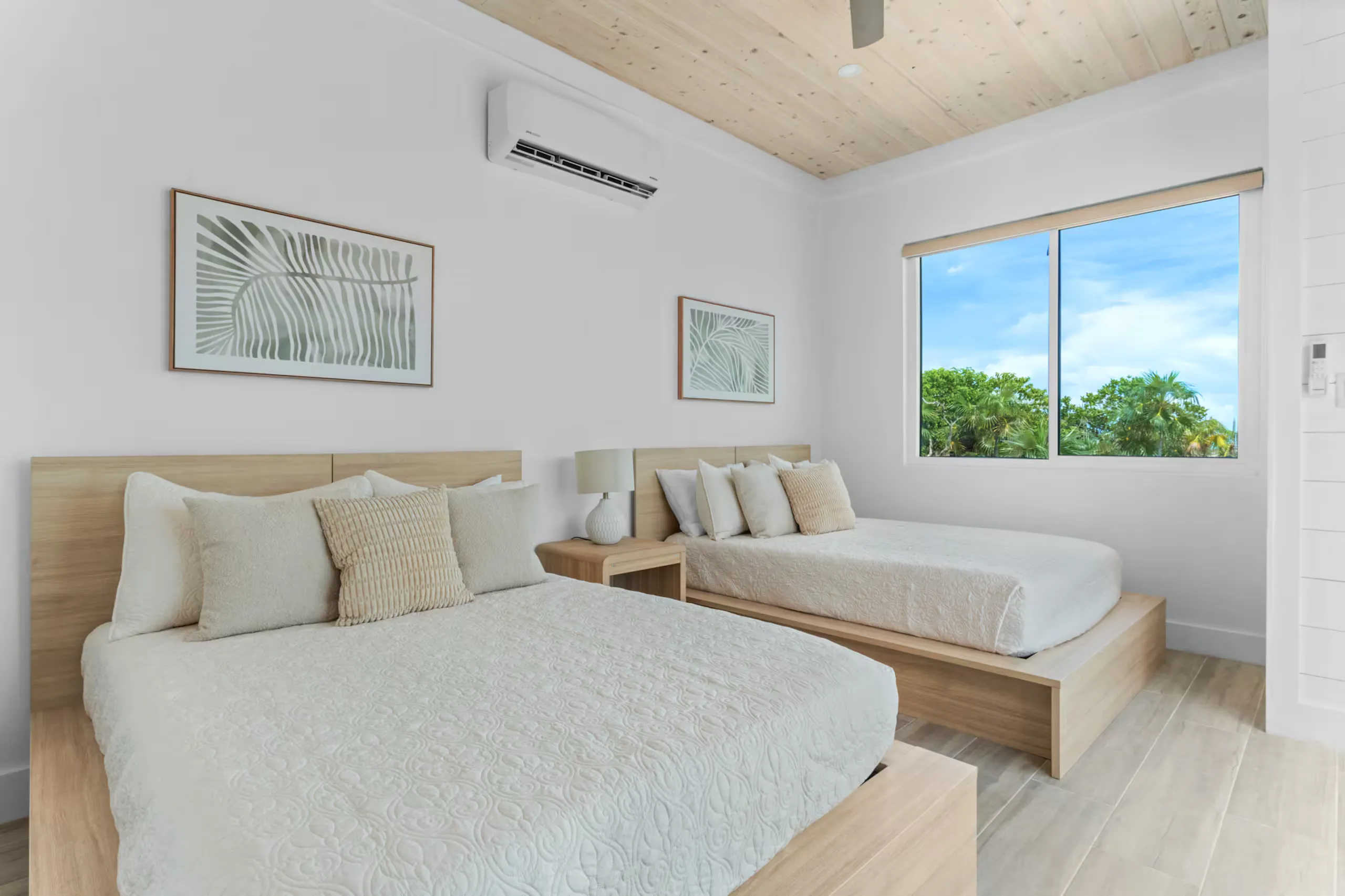 Bedroom with two queen beds and palm-leaf artwork